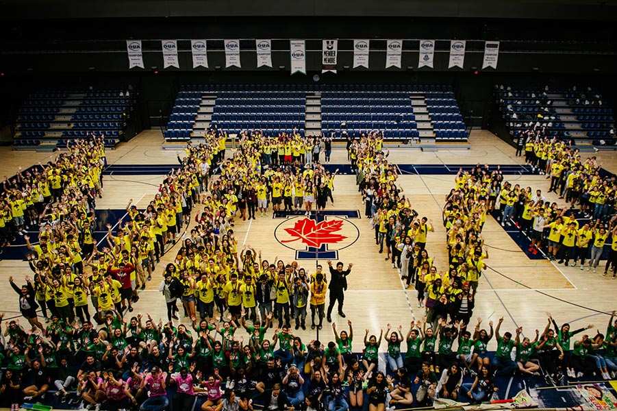 A large group of new students and orientation leaders form the word "NEW" with their bodies during New Roots 2019/2020.